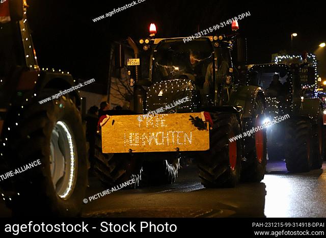 15 December 2023, North Rhine-Westphalia, Kürten: A glowing ""Merry Christmas"" sign is attached to a tractor during a tractor light drive