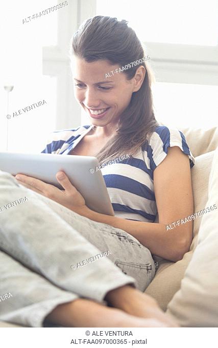Young woman relaxing at home using digital tablet