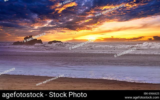 Dramatic sunset on the beach, rocks in the surf, Essaouira, Atlantic coast, Marrakech-Safi, Morocco, Africa