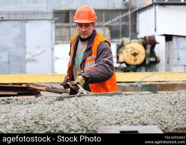 RUSSIA, ZAPOROZHYE REGION - DECEMBER 19, 2023: An employee levels fresh concrete at a plant of reinforced concrete structures in the city of Berdyansk