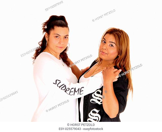 Two lovely young woman, Caucasian and East Indian, hugging each.other, isolated for white background.