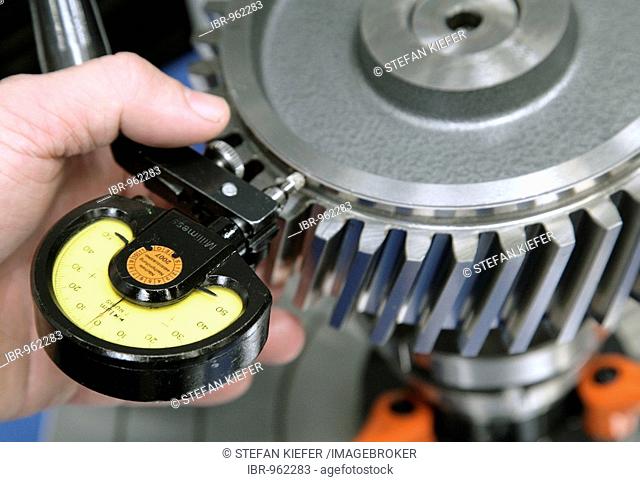 An employee of the Heidelberger Druckmaschinen AG checking the axial and radial runout of a gear with a dial gauge, in the manufacture of offset-printing...