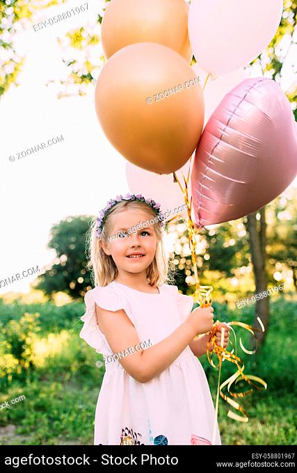 Small shiny girl with pink balloons in the garden. High quality photo