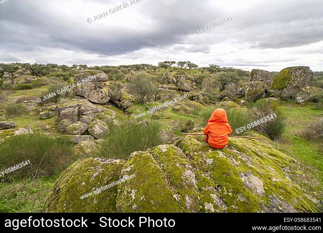 Child boy observing spectacular granitic landscape of Cornalvo Natural Park, Extremadura, Spain