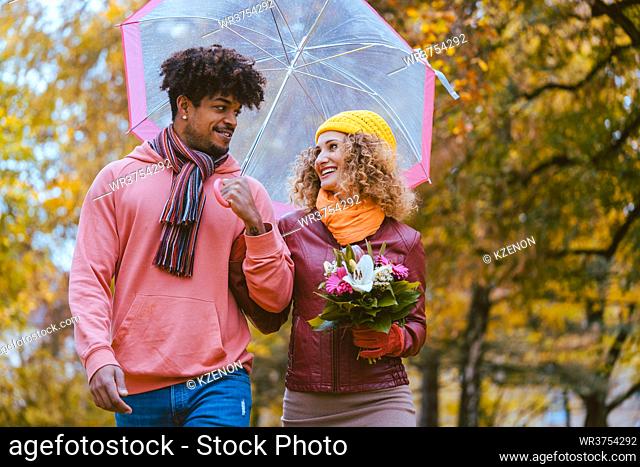 Couple with different ethnicities having a autumn walk in the park full of fall colors