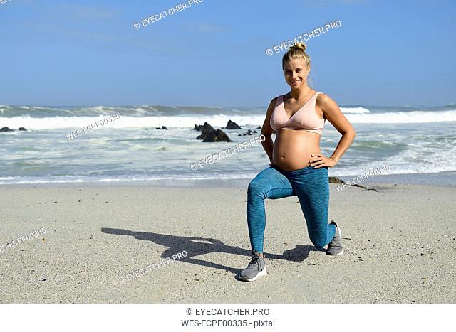 Smiling pregnant woman practicing on the beach