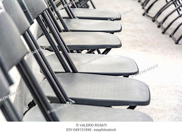 Rows of black folding chairs empty in a conference room