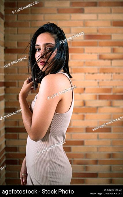 Portrait of beautiful brunette young woman at a brick wall