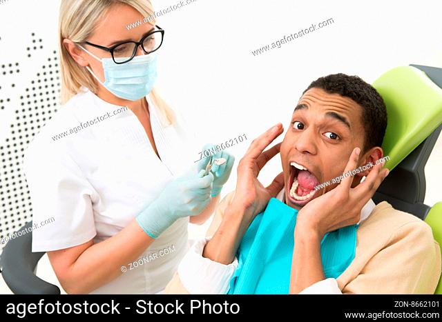 Young man looking frightened, because he is afraid of dentists. Man screaming and shouting at dentist#39;s office