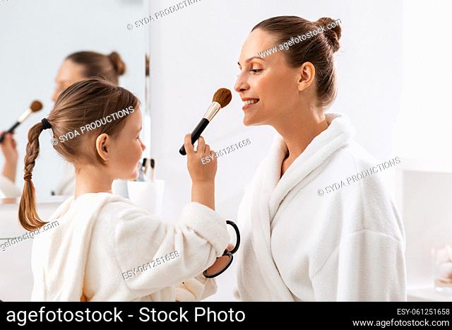 mother and daughter applying make up in bathroom