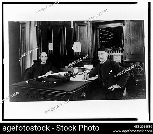 Two Treasury Department employees seated at desk in office, between 1884 and 1930. Creator: Frances Benjamin Johnston