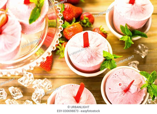 Homemade strawberry popsicles made in plastic cups