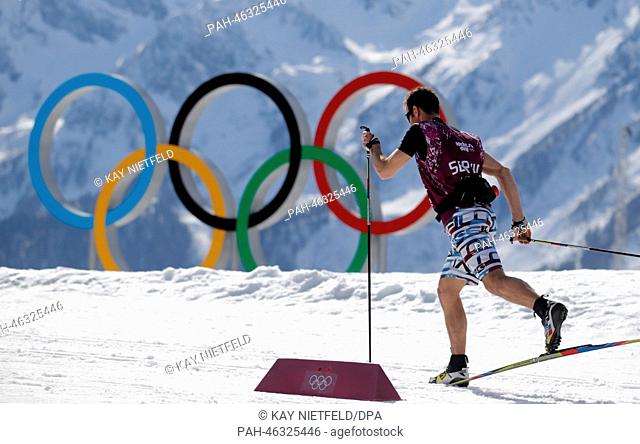 TV Co-Commentator and former cross country coach Adriano Iseppi of Switzerland wears shorts on the Cross Country skiing trail in front of the Olympic Rings...