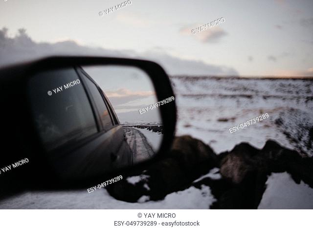 The view in the back window of a car onto a snow covered landscape in Iceland