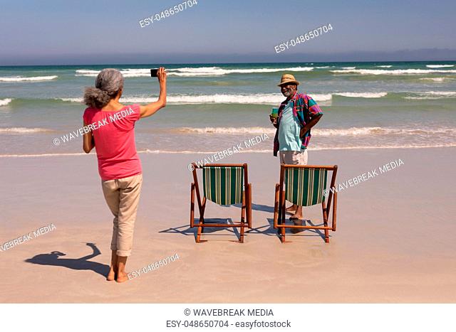 Senior woman clicking photo of senior man on beach