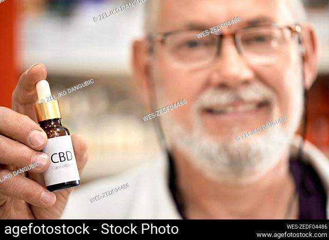 Pharmacist holding bottle of cannabis oil at pharmacy