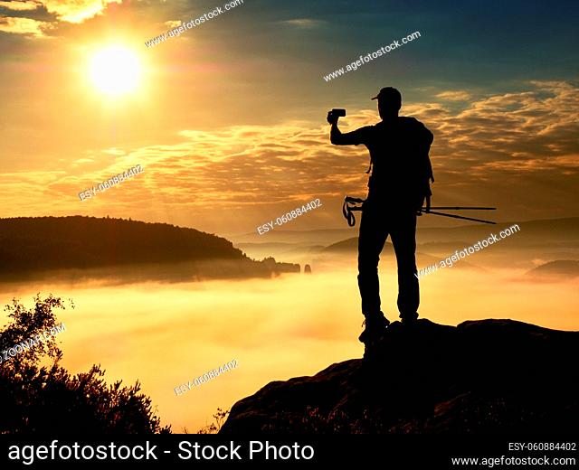 Strong man hiker photogrphy with smart phone at mountain peak. Marvelous daybreak