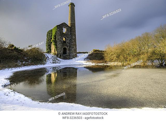 The Cornish engine house and pool on United Downs in Cornwall bathed in early morning light. The image was captured using a long exposure after a snowfall in...