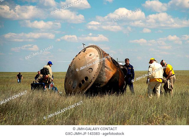 Russian support personnel work around the Soyuz TMA-19M spacecraft after it landed with Expedition 47 crew members Tim Kopra of NASA