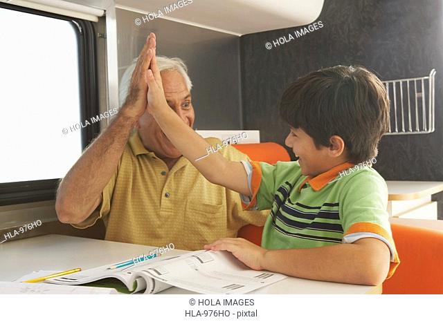Senior man giving high-five to his grandson and smiling