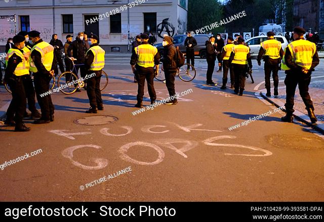 28 April 2021, Saxony, Leipzig: Police officers stand on a street in Leipzig-Connewitz with the words ""Fuck Cops"" spray-painted on the roadway