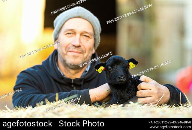 10 January 2020, Lower Saxony, Niederohe: Carl Wilhelm Kuhlmann, shepherd, holds a few hours old toy lamb in his hands. In the Lüneburg Heath the lambing season...