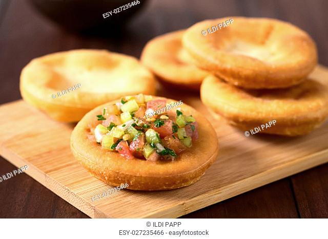 Traditional Chilean Sopaipilla fried pastries made of a bread-like leavened dough, one sopaipilla served with Chilean pebre salsa on top