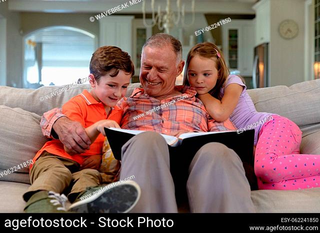 Grandfather and grandchildren at home in the living room