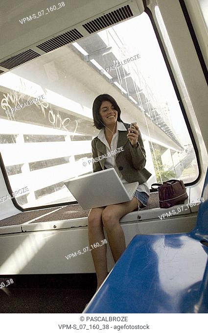 Businesswoman wearing headphones with a laptop on her lap