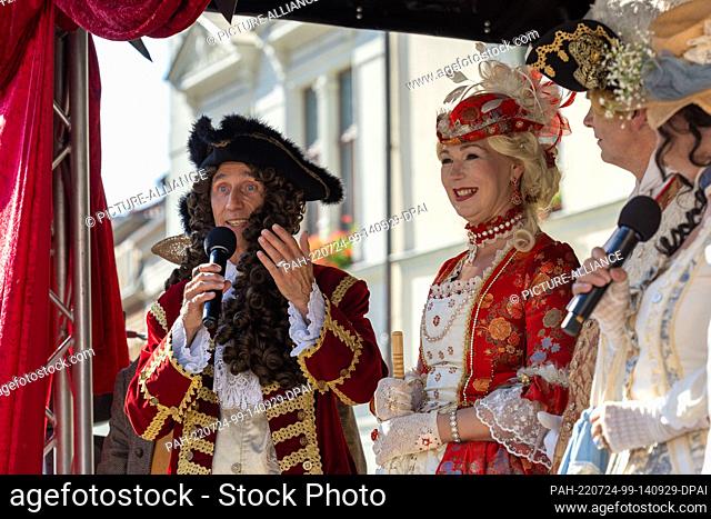 24 July 2022, Saxony, Pirna: Performers of King August III (l) and Queen Maria Josepha (2nd from left) act on the stage located in the town's market square