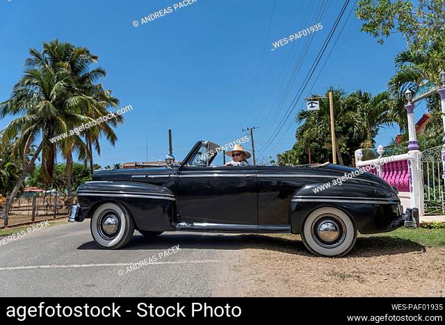 Woman in a vintage convertible car on Cuba