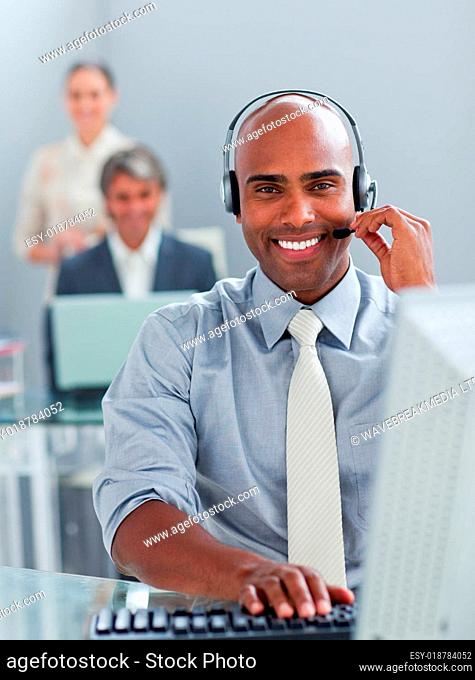 Ethnic businessman working at a computer with headset on