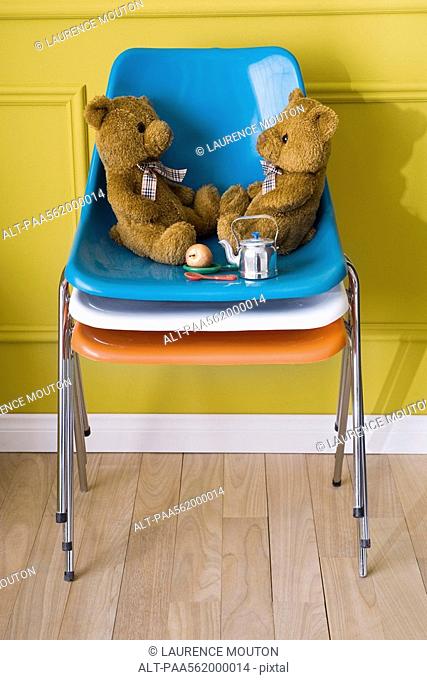 Teddy bears sitting face to face on stack of chairs