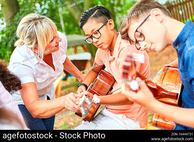Lehrerin und Kinder im Gitarrenkurs im Sommercamp beim Üben für die Talentshow
