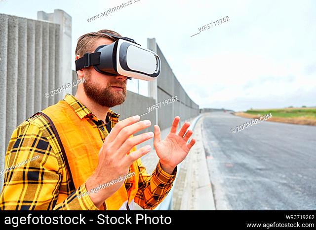 Arbeiter mit VR-Brille bei virtueller Bauplanung auf Baustelle im Straßenbau der Zukunft