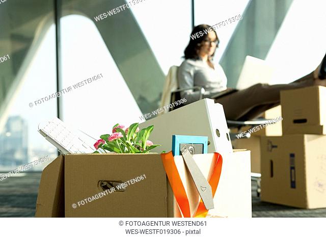 Cardboard box on office floor with businesswoman in background
