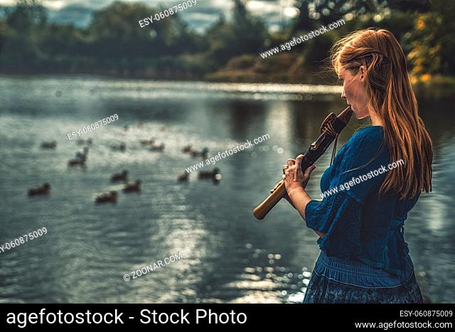 beautiful shamanic girl playing on shaman flute in the nature