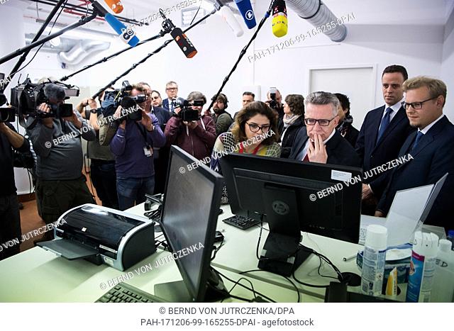 Federal interior minister Thomas de MaiziÃ¨re (3-R) is shown the new identification system by project leader Justus Struebing (R)