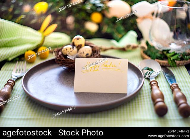 Festive table setting for Easter holiday dinner decorated with flowers and eggs