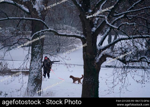 05 December 2023, Hamburg: A woman walks through the ""Planten un Blomen"" park with a dog. Photo: Marcus Brandt/dpa. - Hamburg/Hamburg/Germany