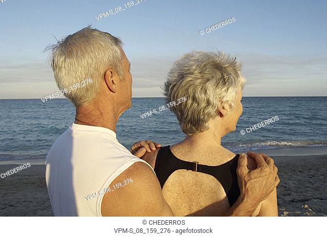 Side profile of a senior man with his hands on a senior woman's shoulders