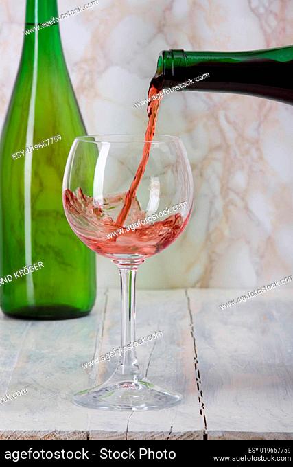 Rotwein wird aus einer Flasche in ein Glas gegossen