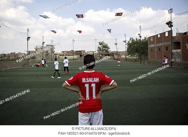 A picture made available on 21 May shows an Egyptian boy, wearing the jersey of Liverpool's Mohamed Salah, practising football at a field