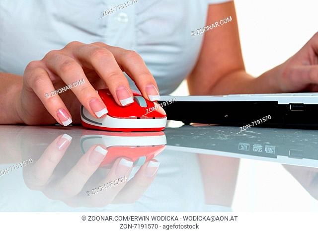 Eine Frau arbeitet in einem Büro und hät die Maus eines Computers in der Hand