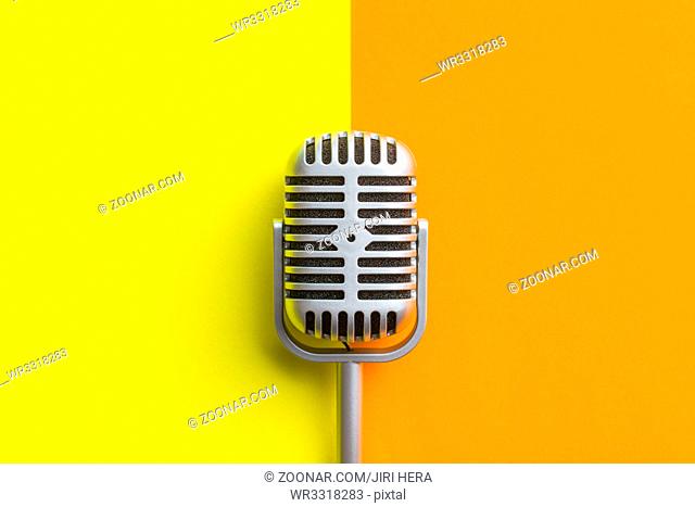 Flat lay of retro microphone on double colorful background