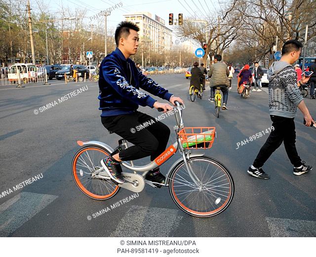 A man rides a bicycle of the rental bike company 'mobike' on a street in Beijing, China, 28 March 2017. Photo: Simina Mistreanu/dpa | usage worldwide