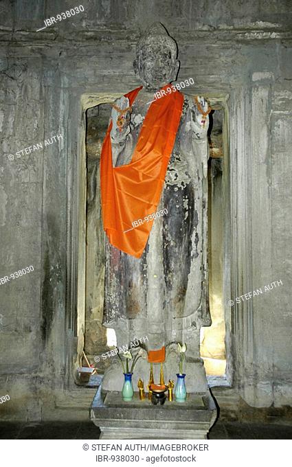 Old statue of a standing Buddha wearing an orange cape, Angkor Wat Temple, Siem Reap, Cambodia, Southeast Asia