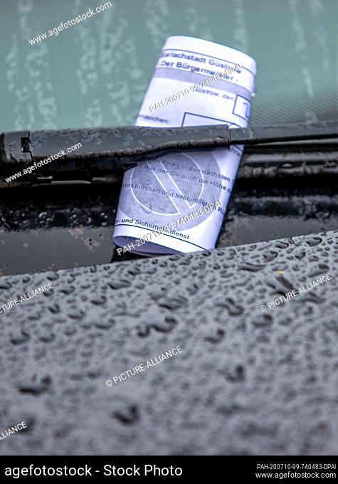 20 June 2020, Mecklenburg-Western Pomerania, Güstrow: A parking ticket is stuck under the windscreen wiper of a car parked in the wrong place when it rains