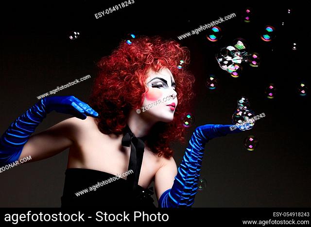 Woman mime with theatrical makeup and soap bubbles. Studio shot