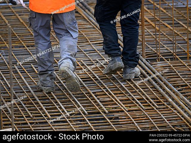 22 March 2023, Saxony, Dresden: Construction workers walk along a reinforced concrete ceiling at the building site of the extension to the headquarters of Carl...